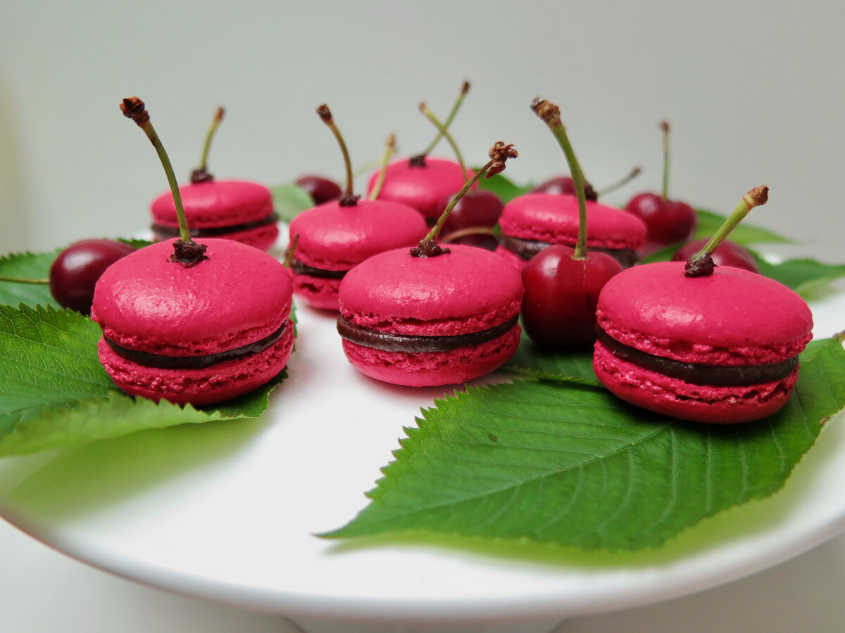 chocolate cherry macarons with stalks as decoration