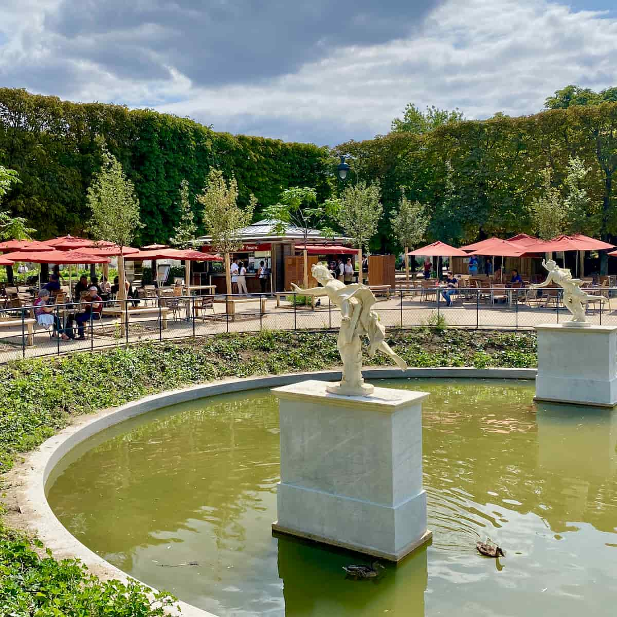 outside restaurant looking on to marble statues in a basin with ducks 