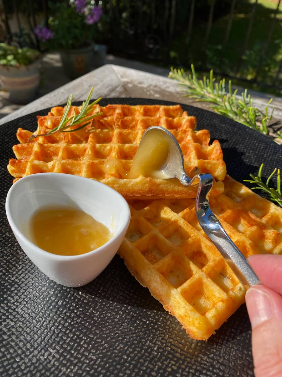 spoonful of honey over golden crispy cheesy waffles
