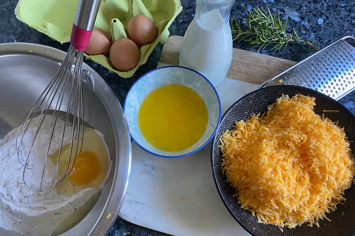 grated orange cheese, melted butter, eggs and flour in separate bowls