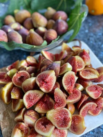 piles of chopped fresh figs in front of whole figs on leaves