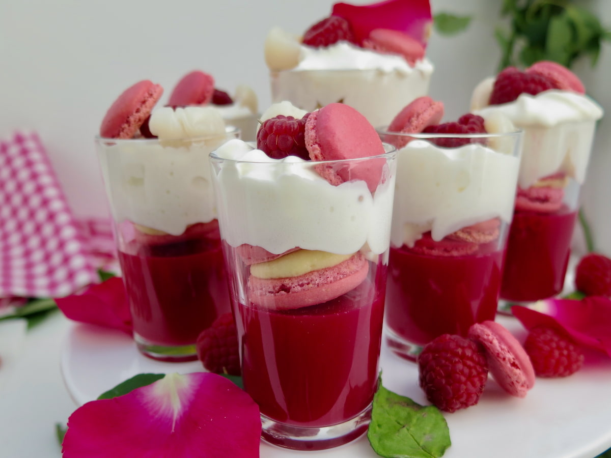 mini shot glasses with dark rose jelly, pink macarons and topped with cream and raspberries