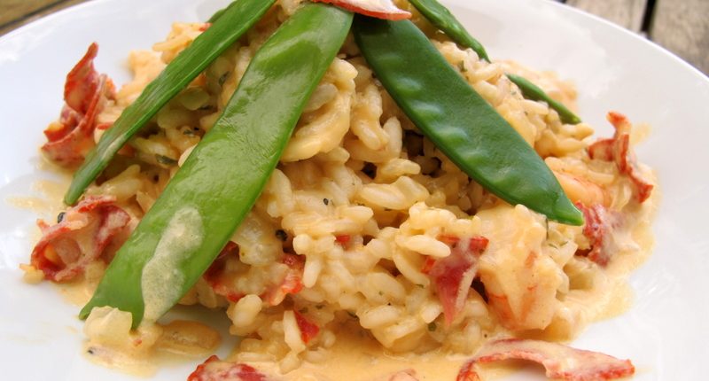 a mound of chorizo risotto in a creamy sauce on a plate topped with mange tout greens