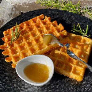 crispy cheese waffles served with a pot of honey and rosemary