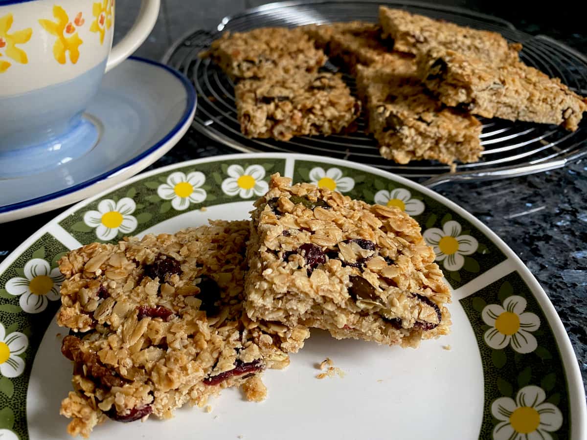 golden oat, fruit and nut square granola bars on plate and cooling rack