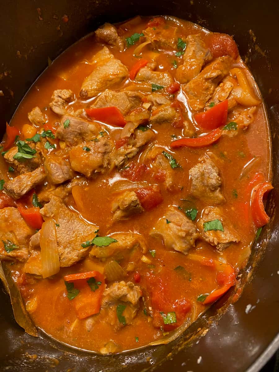 Stew with light meat in a red tomato sauce with peppers and onions and parsley