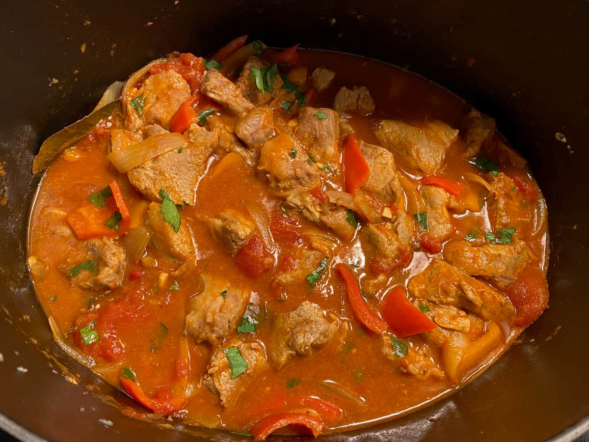 bubbling pot of veal stewing with bell peppers in a tomato and wine sauce