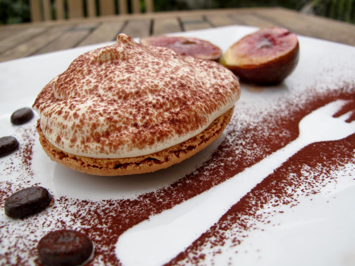 chocolate dusted plate with a giant macaron topped with coffee cream
