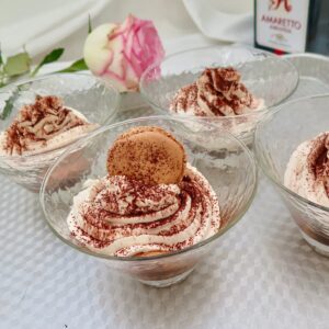 glass dishes of tiramisu dessert topped with macaron shell