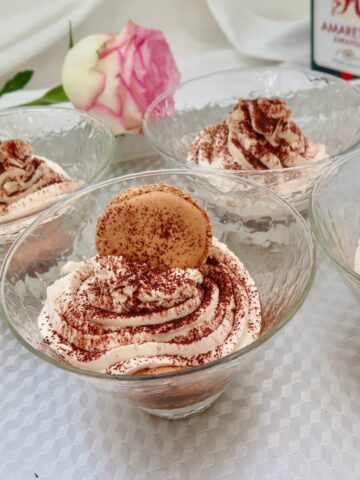 glass dishes of tiramisu dessert topped with macaron shell