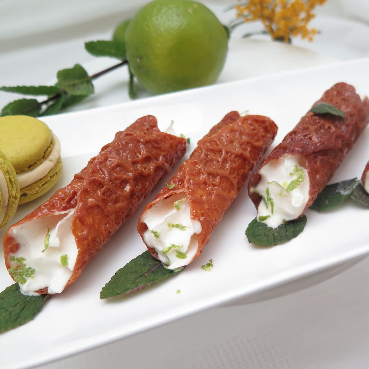 brandy snap tubes filled with lightly whipped cream and garnished with mint leaves and lime