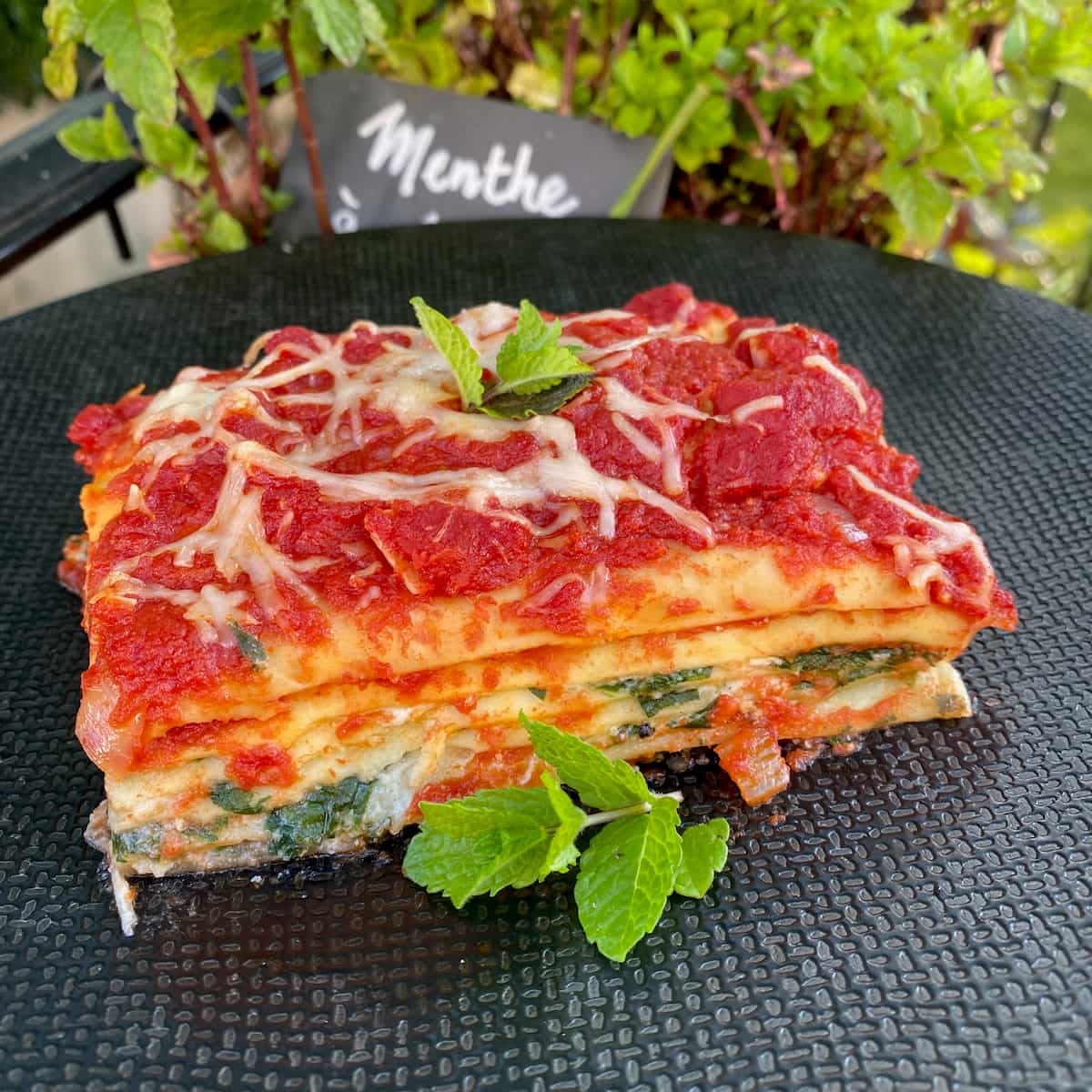 layers of lasagna with cheese, spinach, tomato and mint