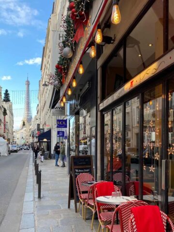 cafe with red tables and chairs outside with view on eiffel tower