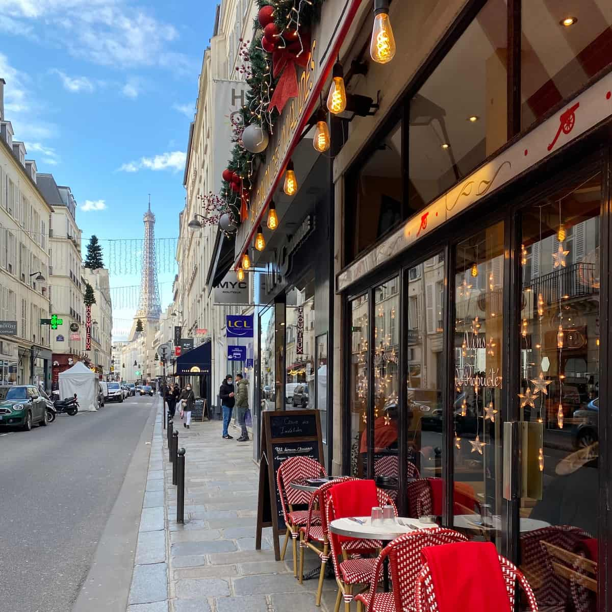 cafe with red tables and chairs outside with view on eiffel tower