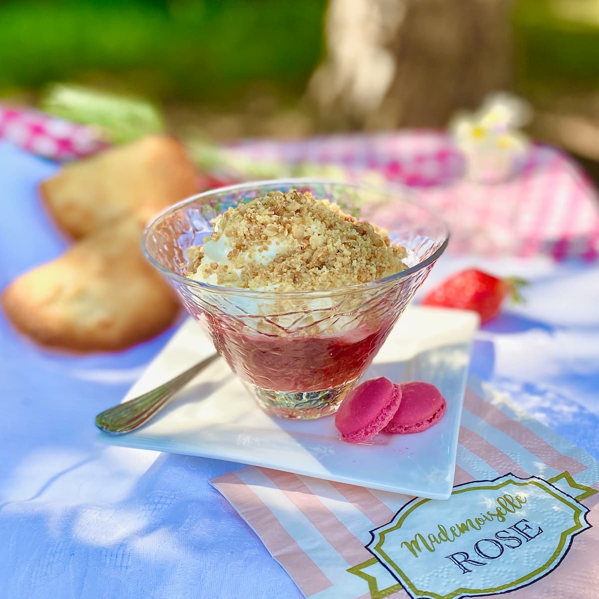 glass dish of rhubarb strawberry crumble with rose macaron shells