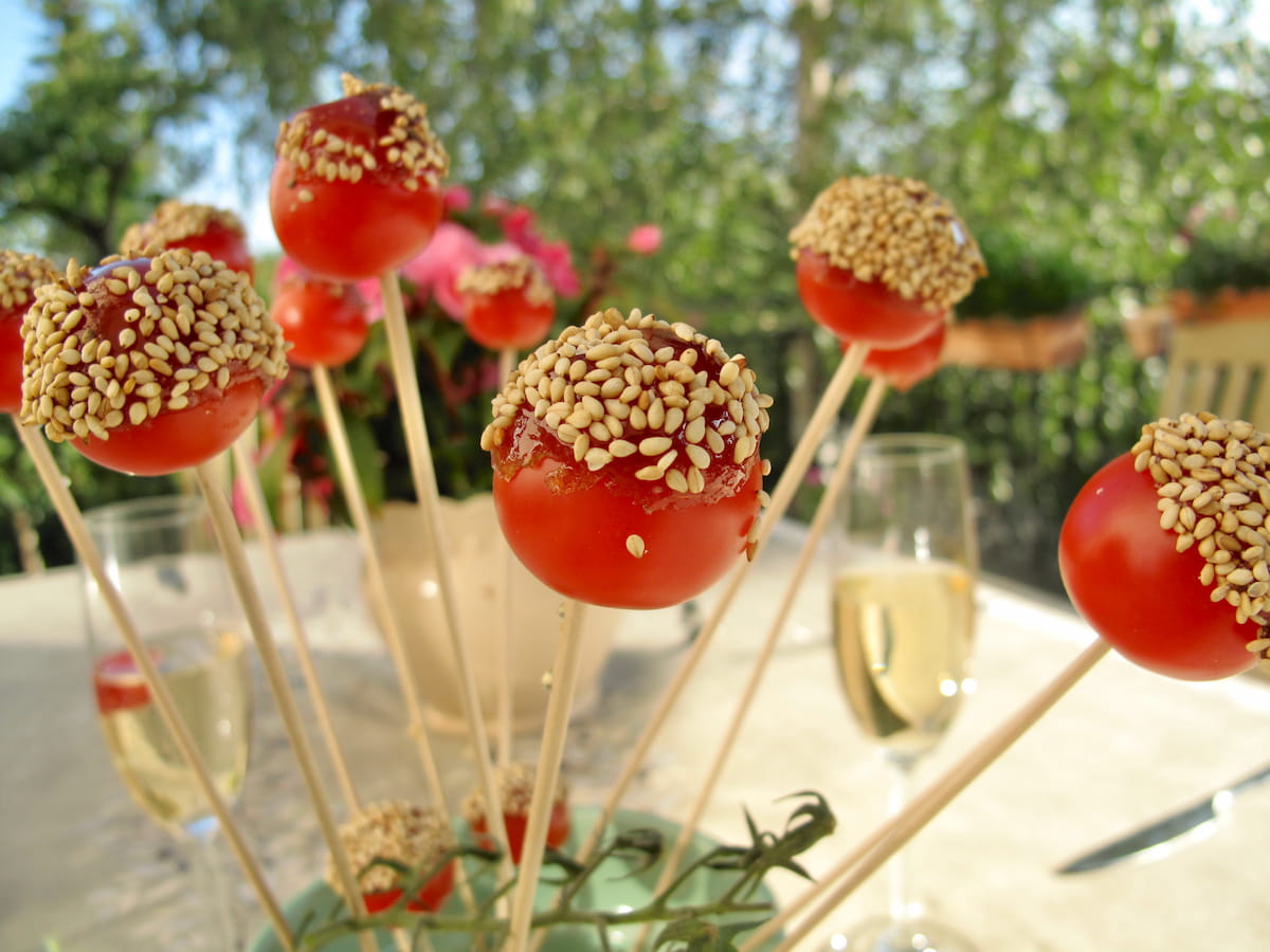 cherry tomatoes on sticks rolled in candy and topped with salted seeds