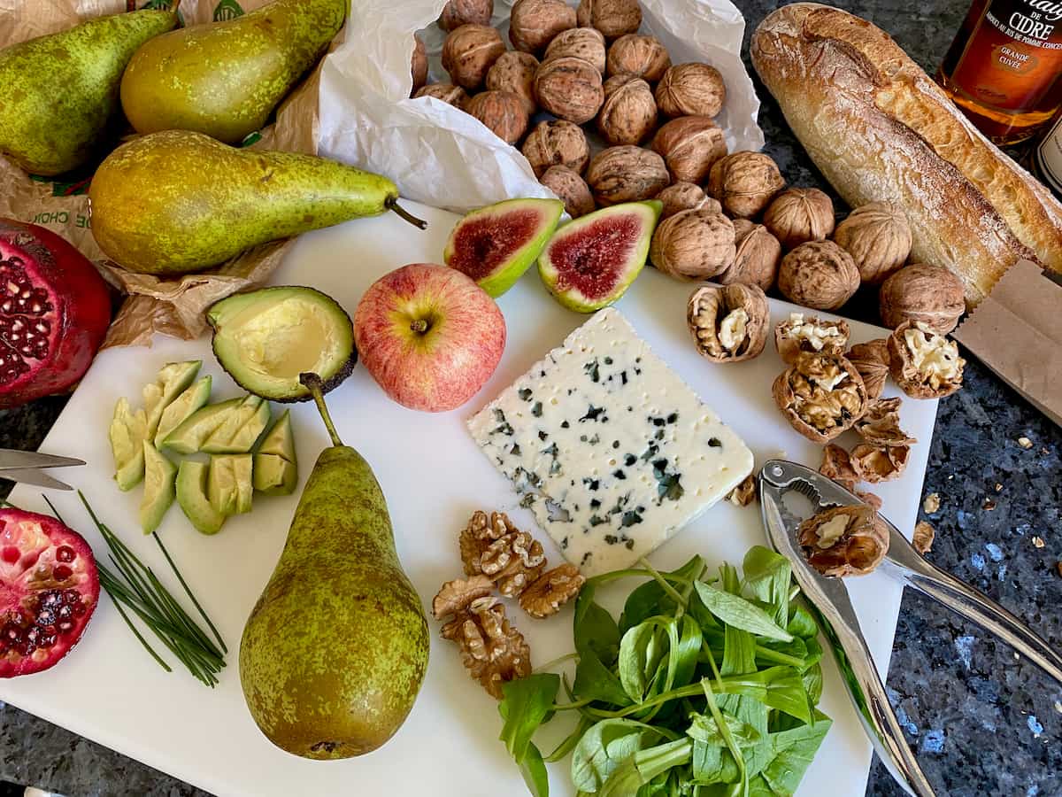 scattered ingredients for a Roquefort salad with a pear, apple, avocado, lamb's lettuce and walnuts