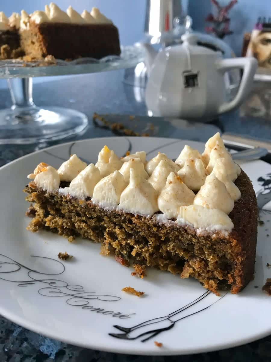 slice of purple carrot cake topped with piped out cream cheese and orange frosting