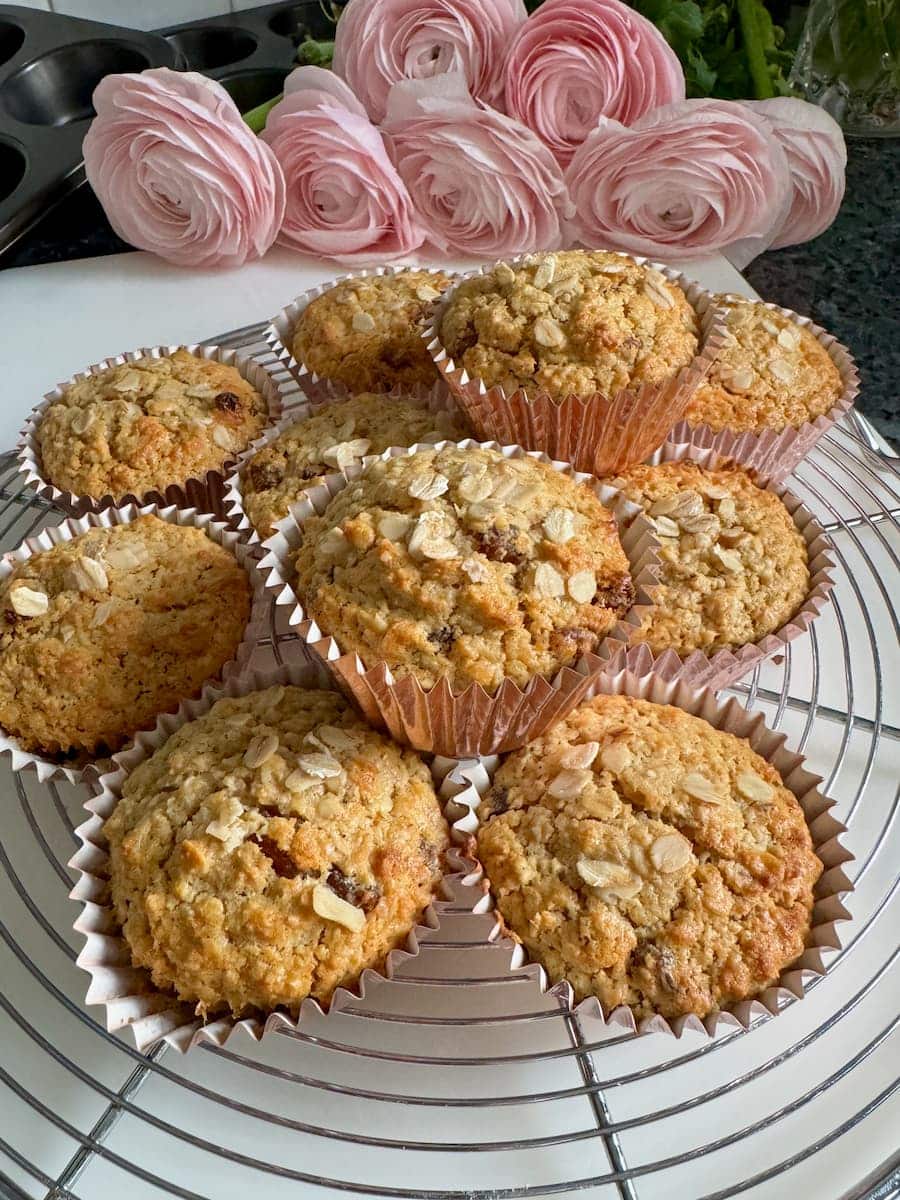 stack of bran muffins topped with oats, cooling on a wire tray