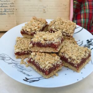 oat crumble squares with a date paste sandwiched in middle, cut on plate with old recipe book and tartan in background
