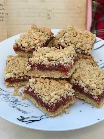 oat crumble squares with a date paste sandwiched in middle, cut on plate with old recipe book and tartan in background