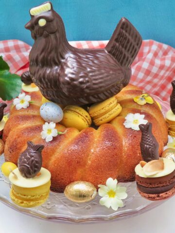 lemon drizzle cake for Easter shaped like a nest topped with chocolate hen, macarons and eggs