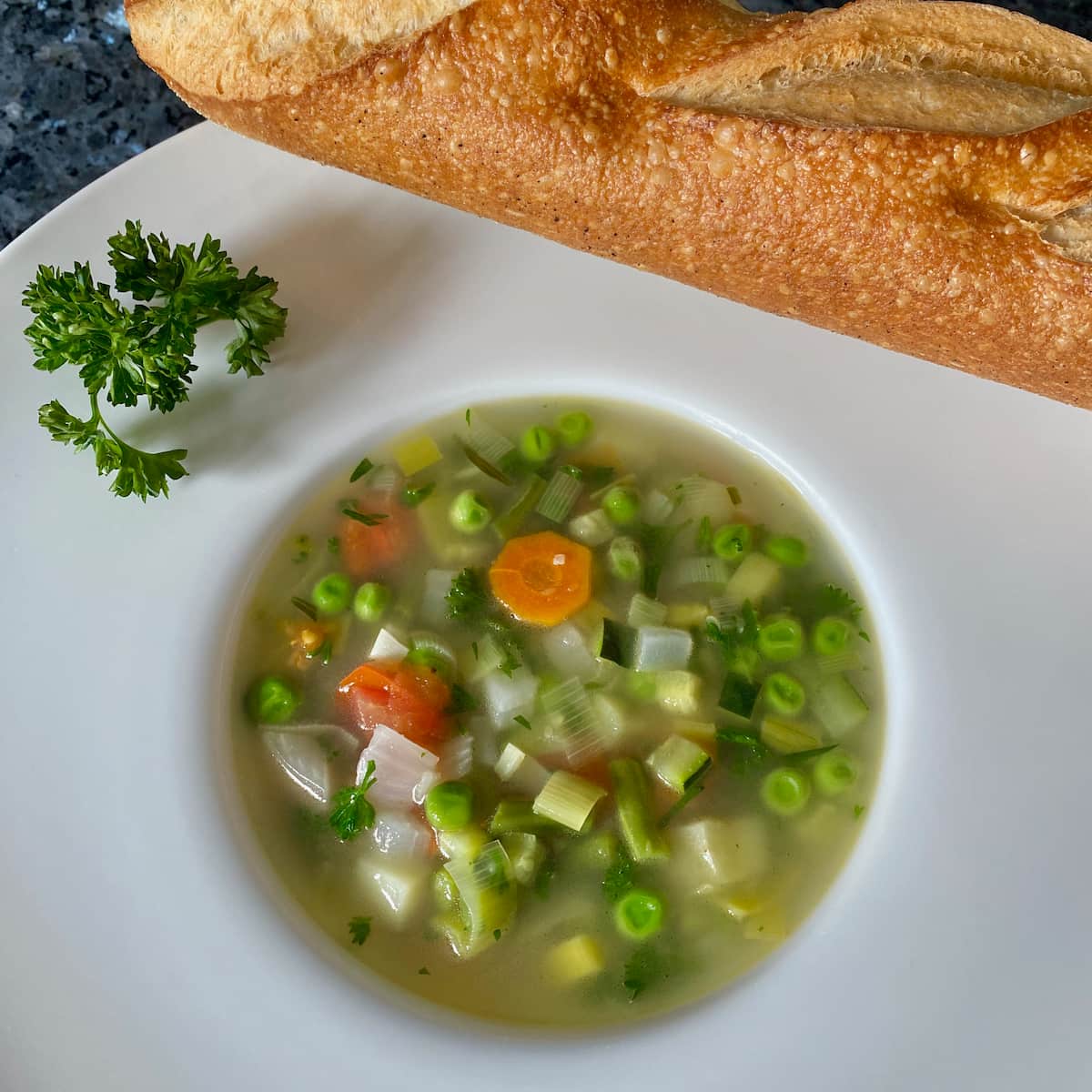 bowl of chunky vegetable soup with French baguette
