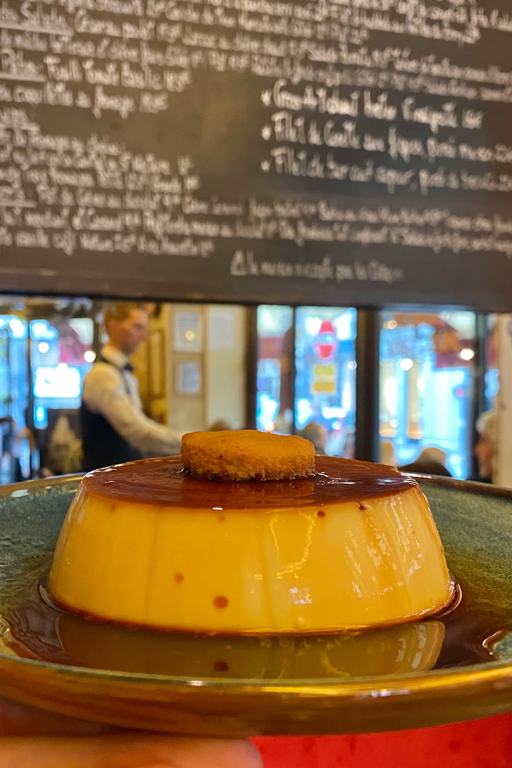 paris cafe waiter serving a creme caramel dessert