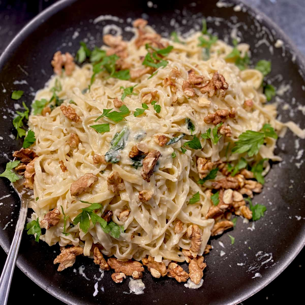 pan of fresh pasta noodles with goat cheese sauce, parsley and walnuts