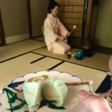 authentic tea ceremony in Japan as a woman is kneeling on the flour pouring water in different pots for tea