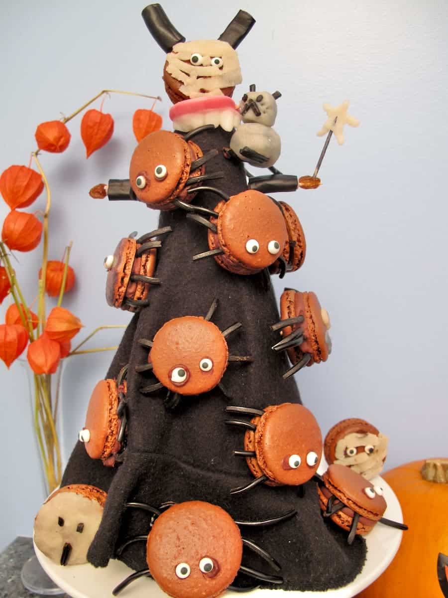 halloween black witch's hat covered in macarons with eyes and liquorice spider legs