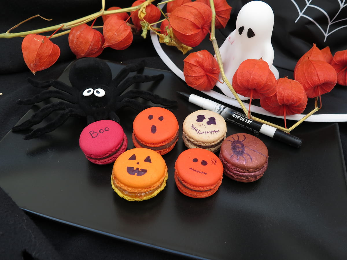 colourful macarons with Halloween faces on black plate with ghost