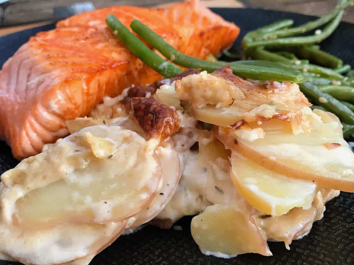 creamy sliced potato gratin served with a salmon steak and French beans