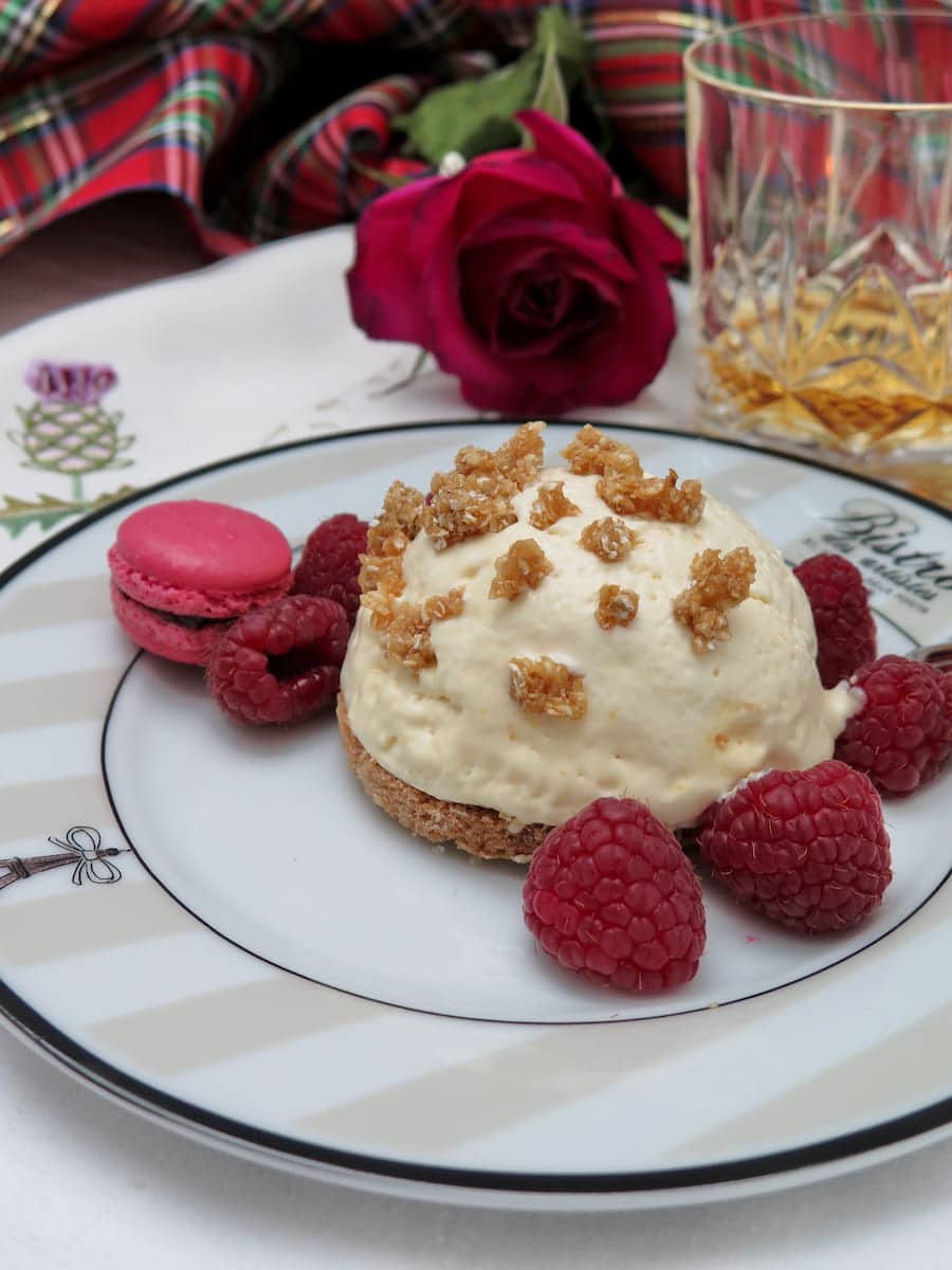 honey ice cream dome on circle of shortbread topped with oat praline and raspberries