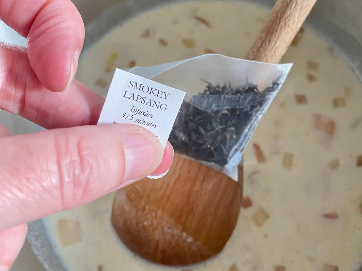 holding a sachet of Lapsang souchong smoked tea over a pan of sauce