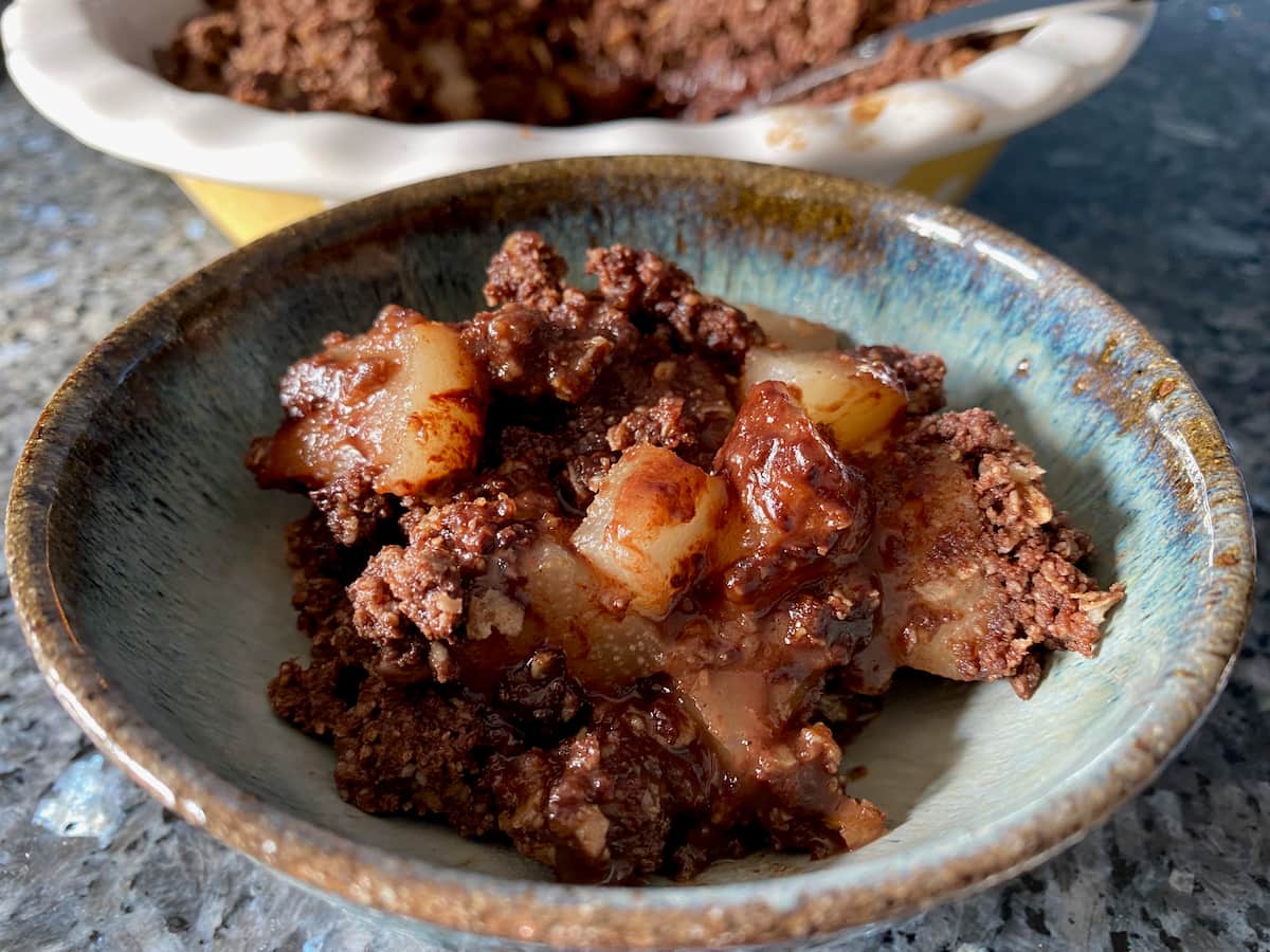 bowl of melted chocolate crumble with juicy pear