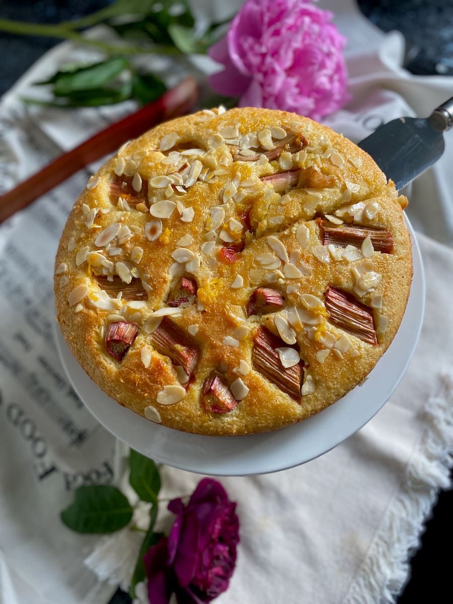 round cake topped with rhubarb surrounded by roses