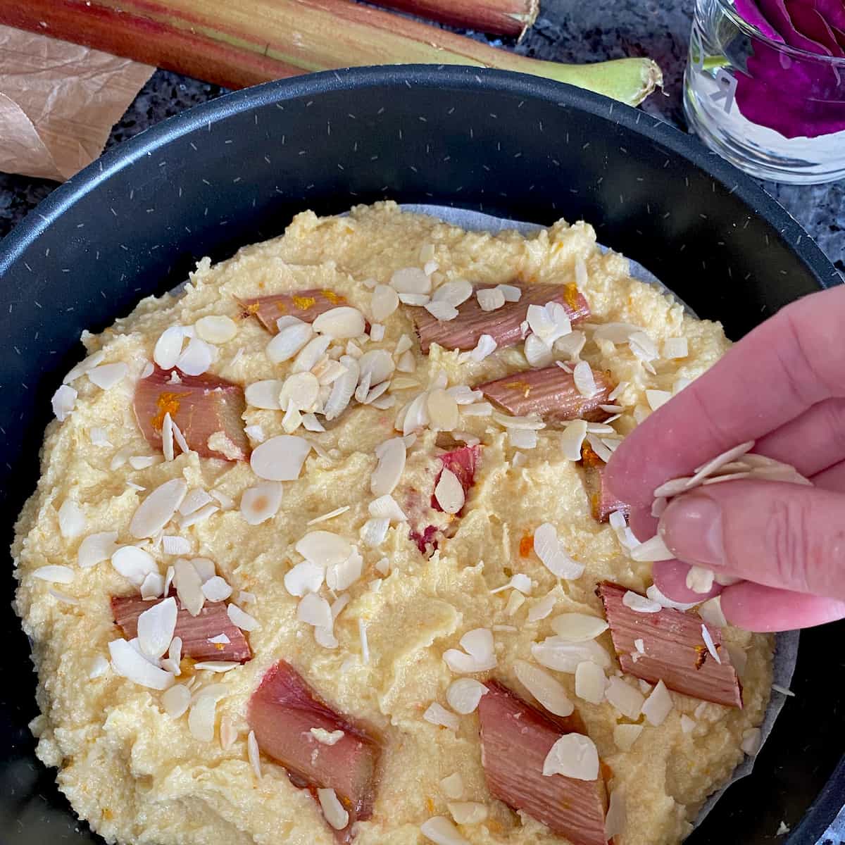 sprinkling over flaked almonds on top of cake batter and rhubarb