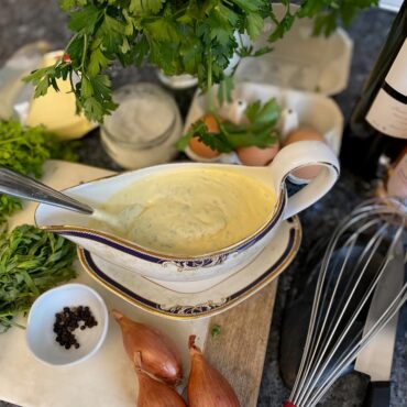 sauce serving dish filled with a creamy yellow herb sauce surrounded by its ingredients