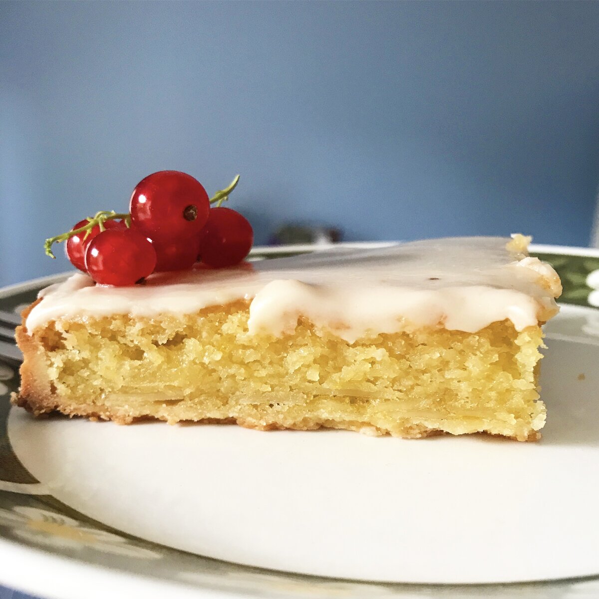 slice of almond cake topped with rum glaze and redcurrants