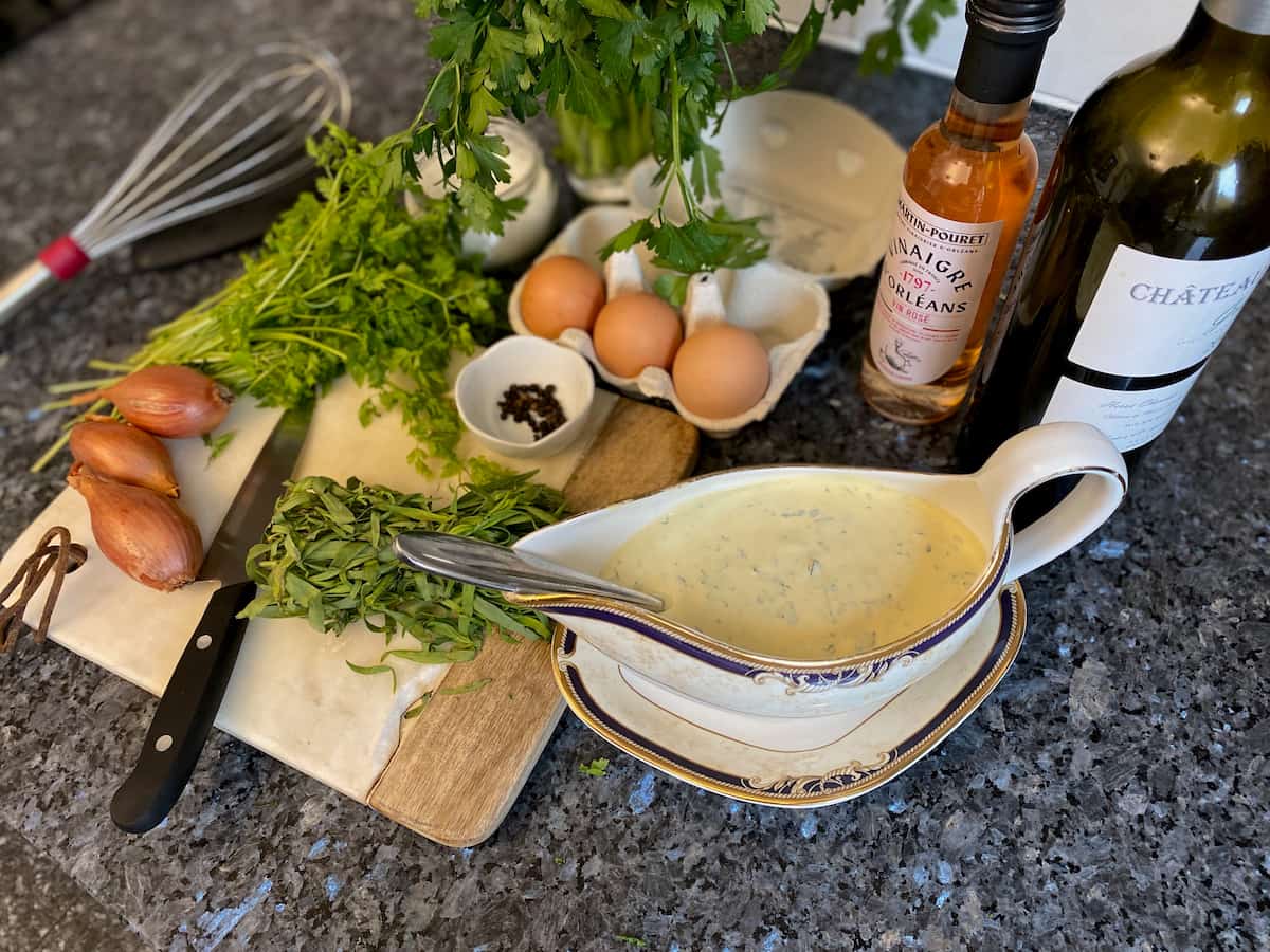 fresh tarragon, chervil, shallots, eggs, pepper, wine and vinegar laid out in front of a sauce boat