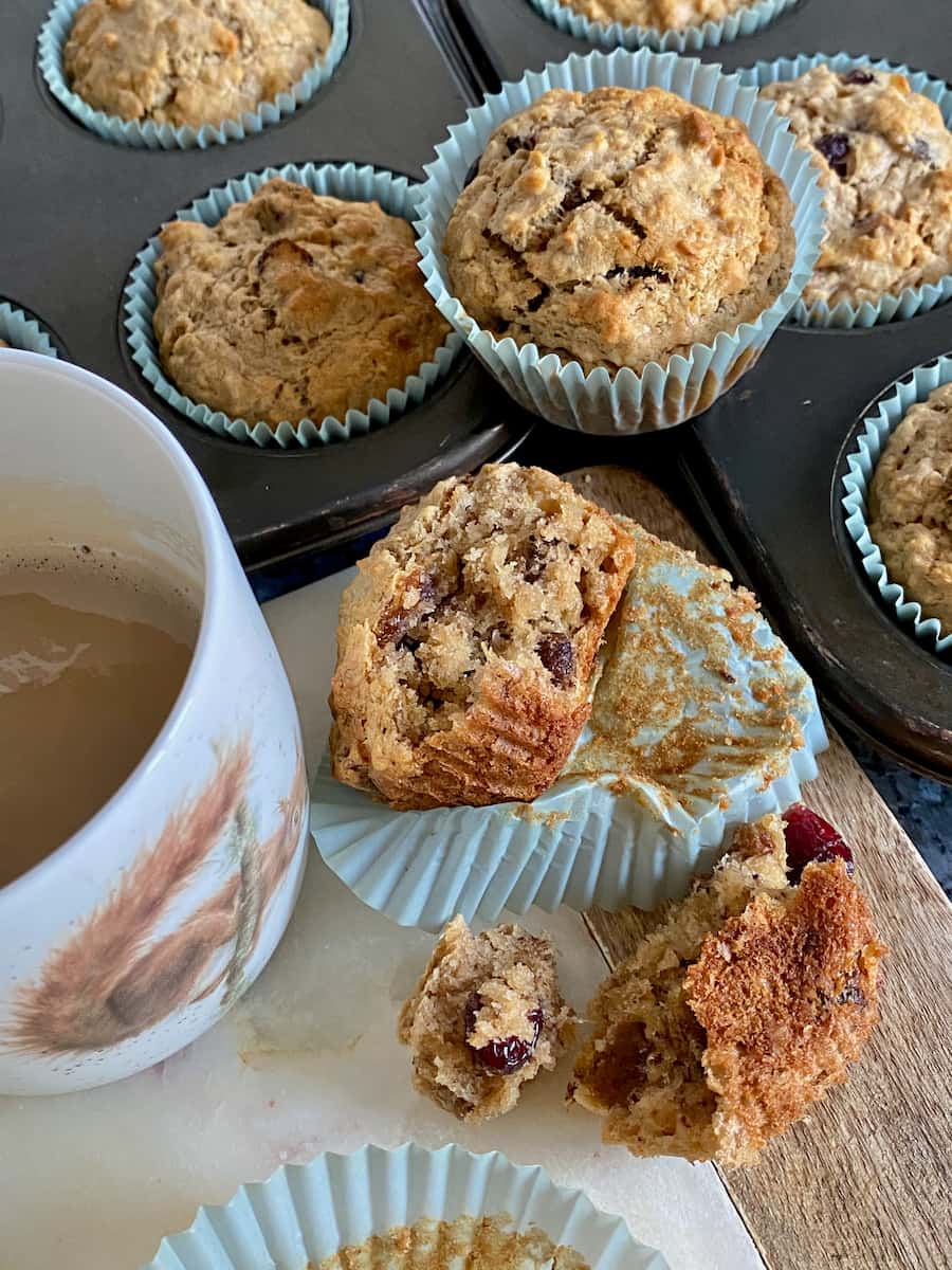 torn apart moist muffins filled with dried fruits and nuts served with a mug of coffee