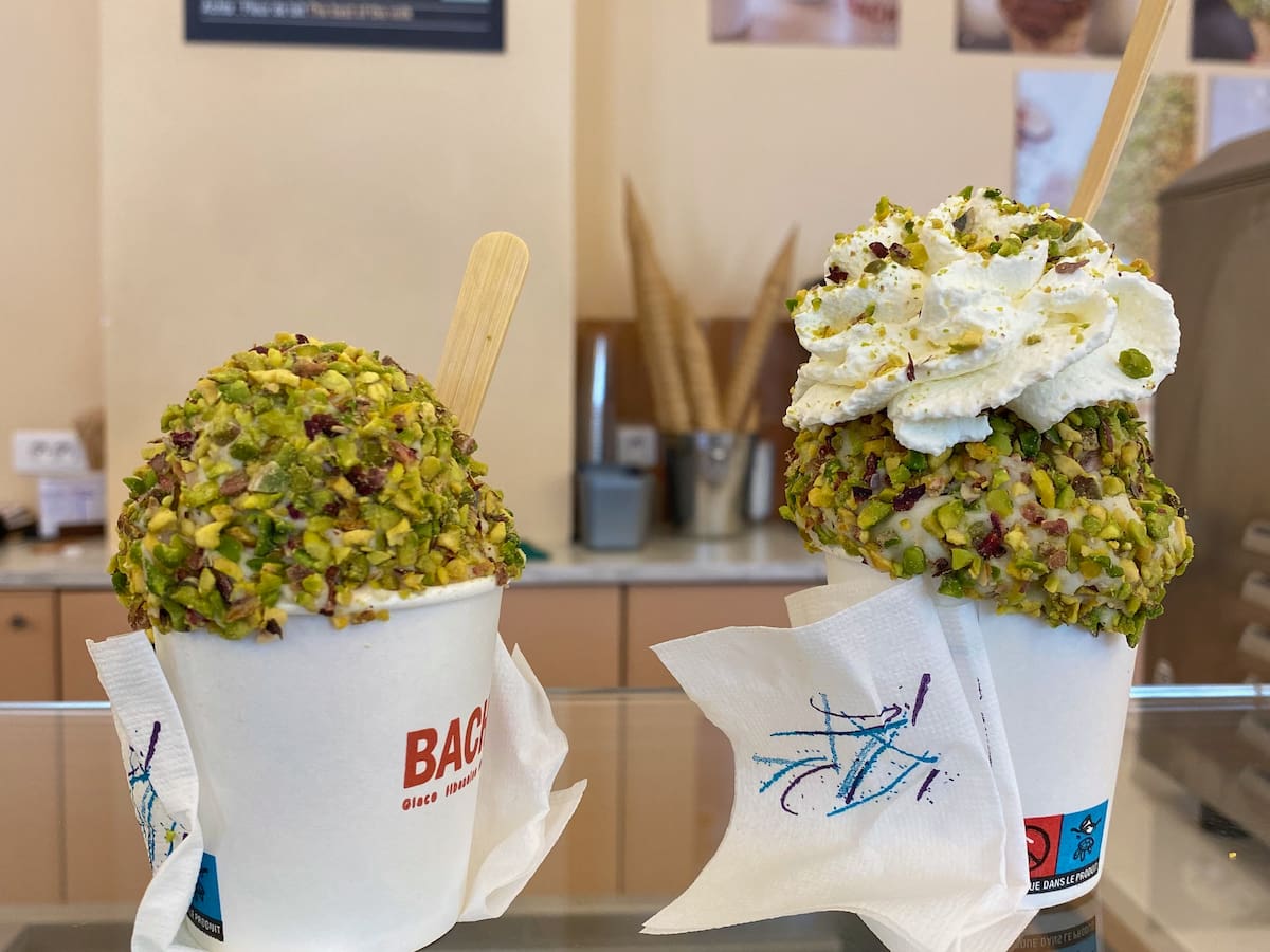 2 pots of ice cream topped with crushed pistachios and cream