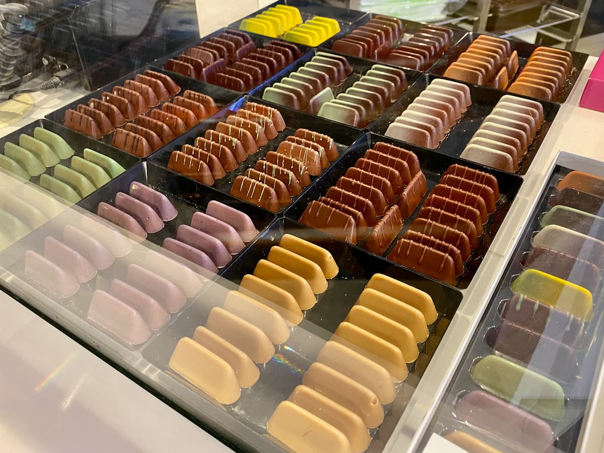 rows of colourful shiny chocolates in a glass case