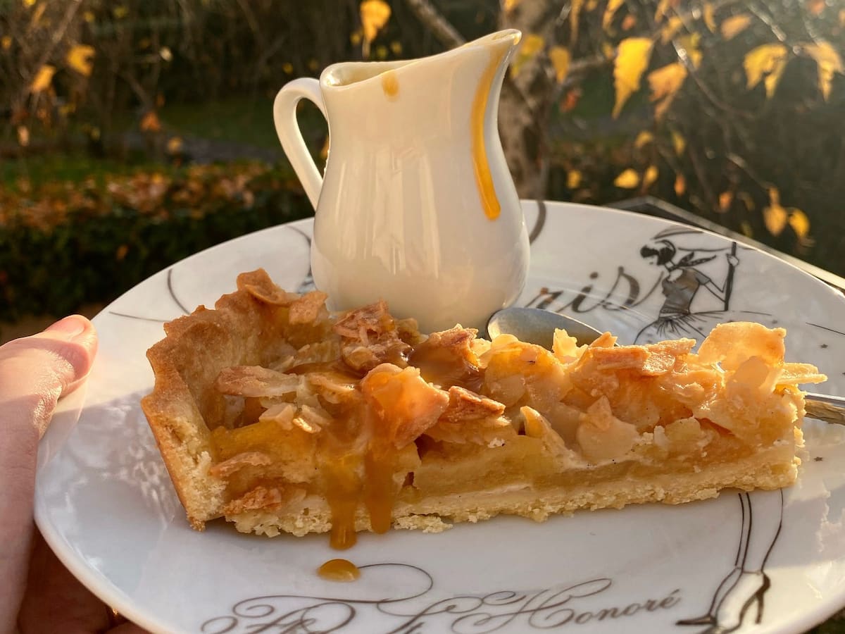 slice of apple nut tart with a pot of golden caramel sauce