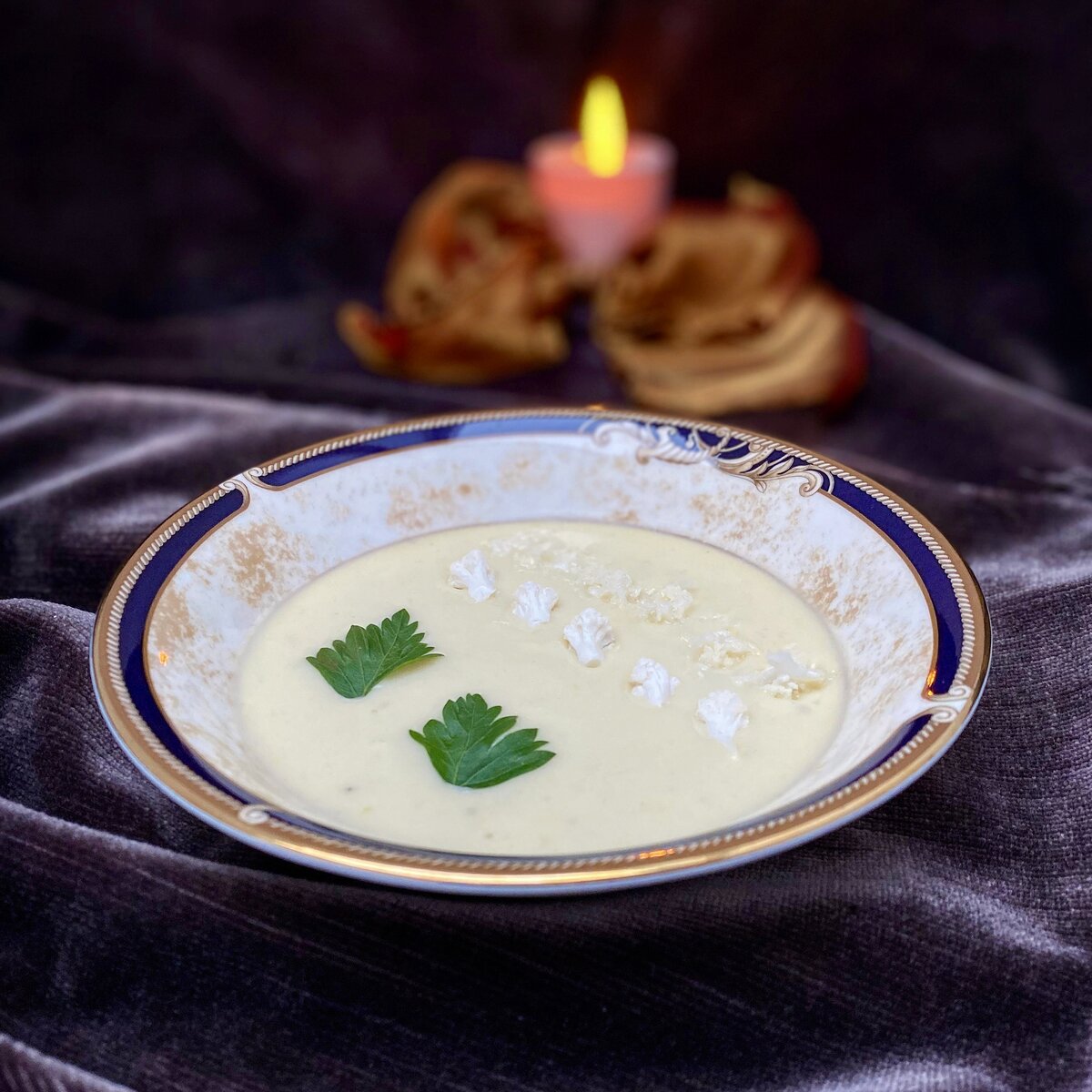 cauliflower soup topped with florets and parsley candlelit