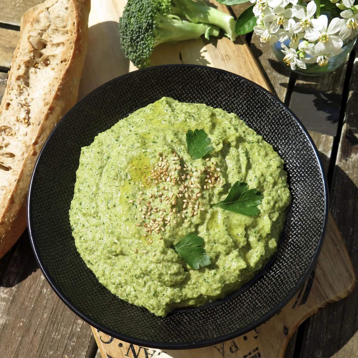 bowl of broccoli hummus spread with a baguette