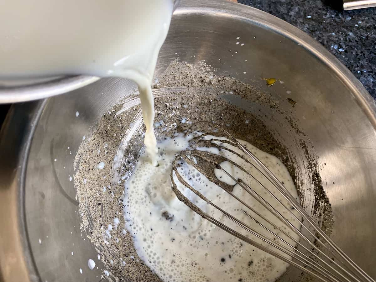 pouring hot milk into a black paste