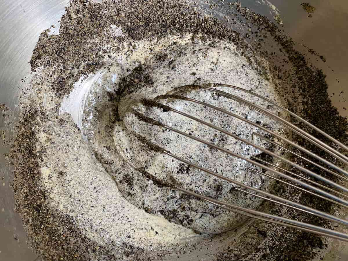 whisking black sesame powder with yolks and sugar in bowl