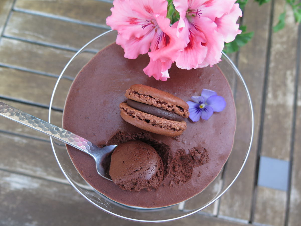 arial view of mousse au chocolat with spoon and a dark chocolate macaron geranium flower